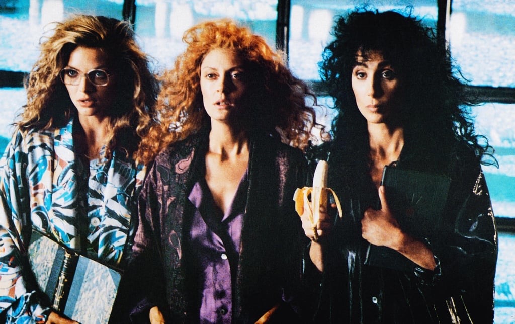 Pfeiffer, Sarandon, and Cher stand side by side with big hair, looking extra as hell with whatever it is they are wearing (jammies? nightgowns? Average 80s clothes? Who knows, it's been ages since I've seen this one). Pfeiffer is sporting glasses and holding a book. Cher is holding a banana.