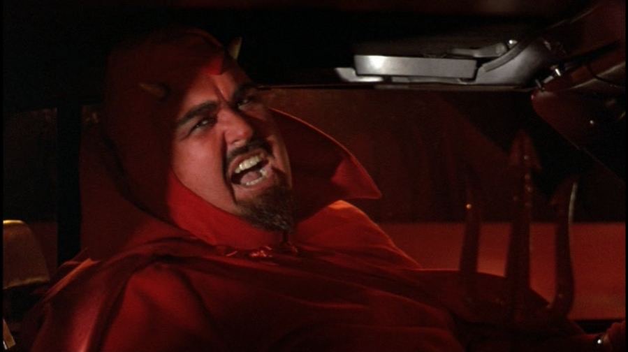 John Candy as the devil, with red face and goatee.