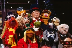 John Denver in a top hat surrounded by Muppets.
