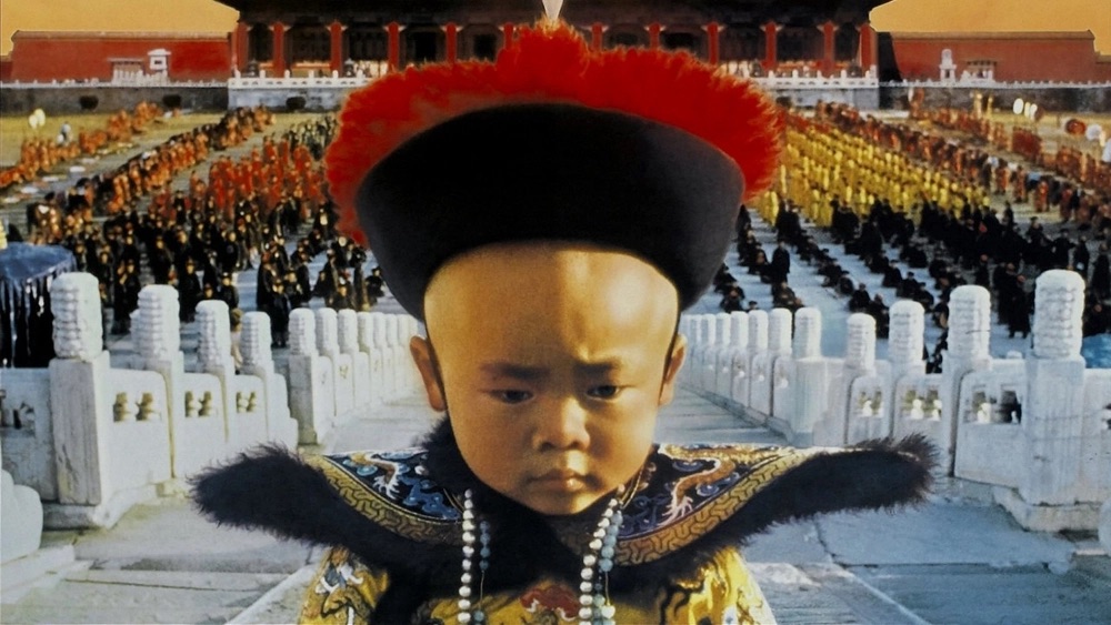 An elaborate-dressed child distanced from a large crowd.
