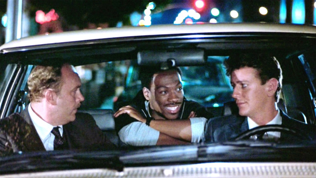 Eddie Murphy smiles engagingly from the backseat of a car.