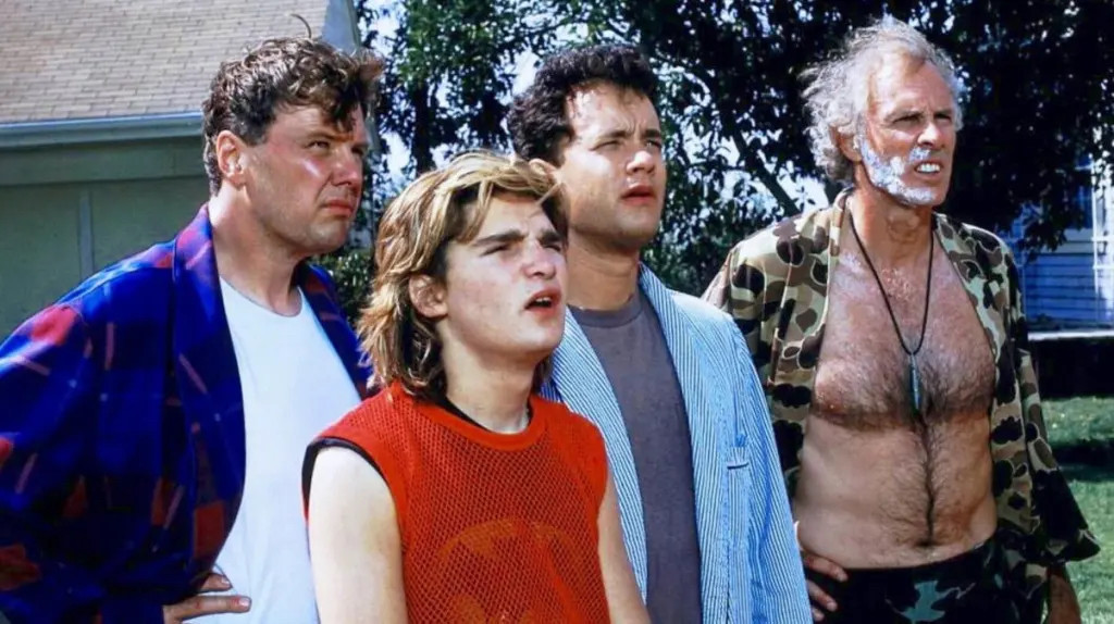 Four men stare off incredulously at something off-camera. One is Tom Hanks in a bathrobe. One is Corey Feldman in, get this, a black Batman tank top with a red mesh tank top over it. Amazing late 80s fashion.