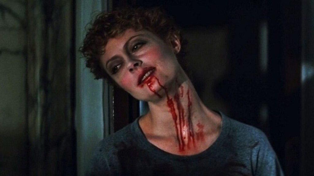 Susan Sarandon with short curly hair! She has her head tilted, blood dripping from her mouth down her neck. She looks dazed and dreamy.