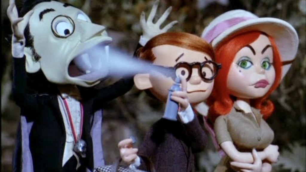Two Rankin-Bass people stand side by side. One sprays something into the mouth of a vampire.