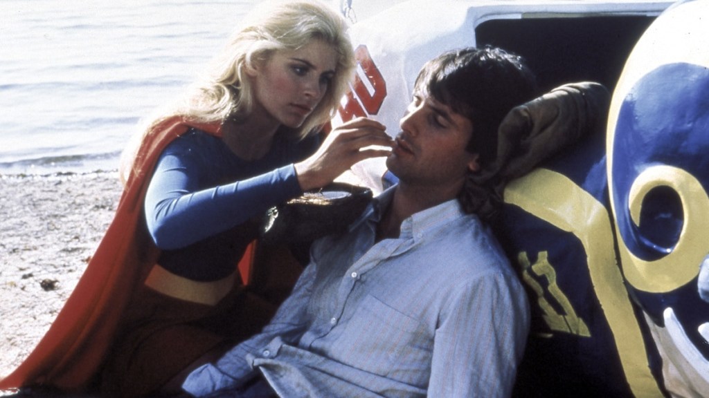 Supergirl seems to be touching the lips of an unconscious man, or giving him something to revive him? She is blonde, beautiful, and Helen Slater.