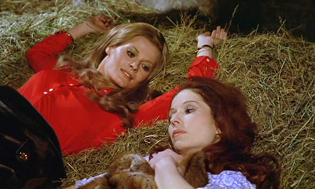 Two women chilling together on top of hay. Just gals being pals.