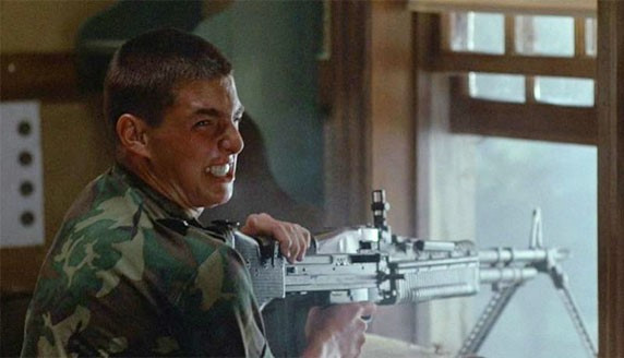 Tom Cruise in camo makes a scrunched-up face while at a rifle pointed through a window. Cannot tell if Shooting Gun-face or Oh God I Killed Someone-face.