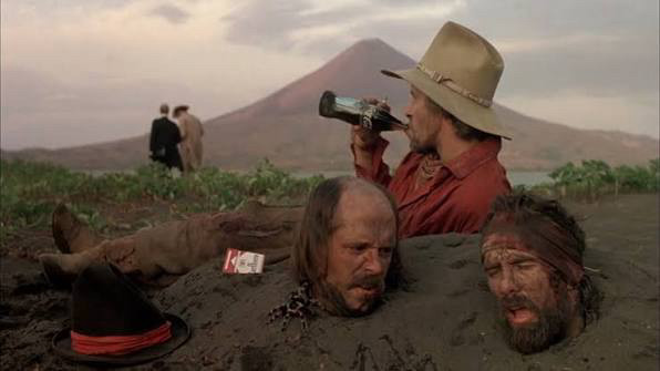 A man drinks a beer next to two guys buried up to their necks. I've seen this Beckett play.