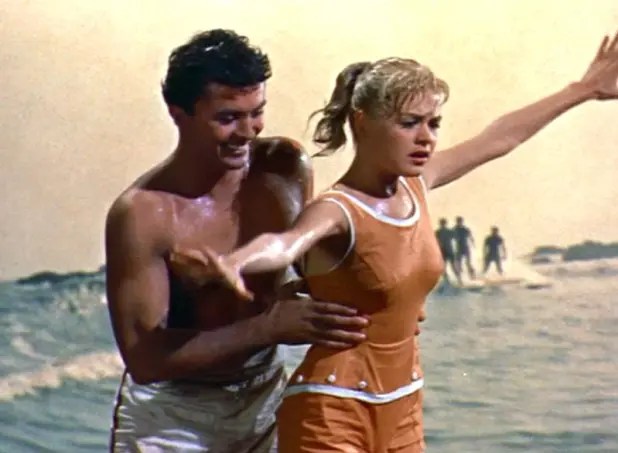A guy who looks too old for her teaches a little blonde Gidget to surf. This lesson should be called Where a waist is, because duder's hands are far too high