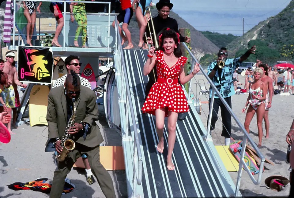 Annette, done up in a red dress with white polka-dots like it's still the 1960s, comes down a walkway to the beach. Fishbone is everywhere.