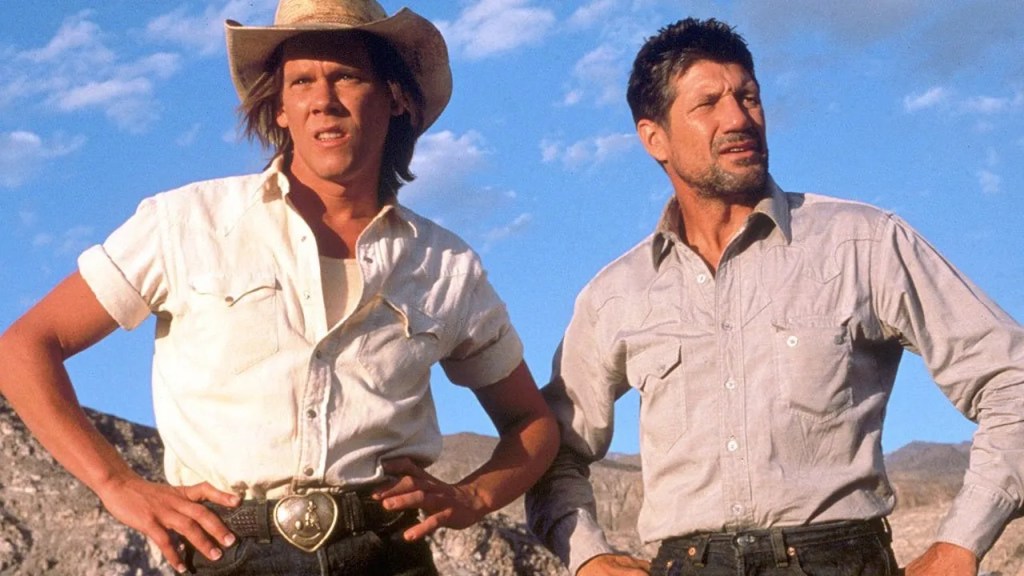 Two manly squinting men, looking manly (Kevin Bacon with a very big belt buckle and Fred Ward)